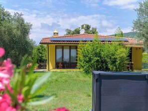 Ein gelbes Gebäude mit einem Ziegeldach, großen Fenstern und einer kleinen Terrasse.