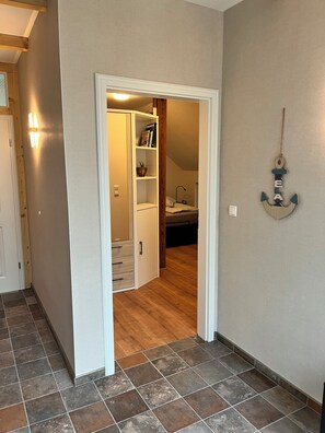 A hallway with a wooden door, a white closet with open doors, and a wall-mounted anchor decoration. - Spacious penthouse apartment for all ages under one roof in an idyllic village setting with a sauna (Rubkow)