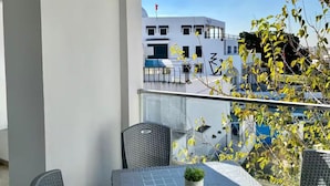 A balcony with a table, chairs, and a potted plant. - Sandra 5 (La Marsa)