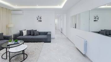 A modern living room with a grey sofa, a round coffee table, and a large mirror.