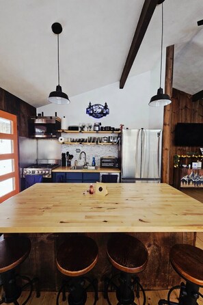 Eine Küche mit Holztisch, Barhocker, Herd und Kühlschrank.