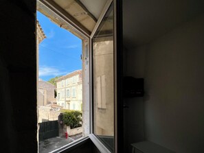 Ein Fenster mit Blick auf ein Gebäude mit Steinmauern und einem roten Hydranten vor der Tür.