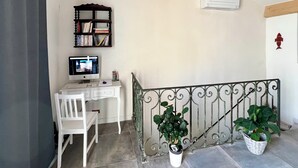 Une pièce comprenant un bureau, une chaise, un ordinateur, une bibliothèque, un climatiseur et des plantes en pot.
