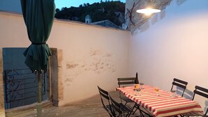 Un espace de restauration en plein air avec une table dressée pour deux personnes, une bouteille de vin et un verre de vin posés sur la table.