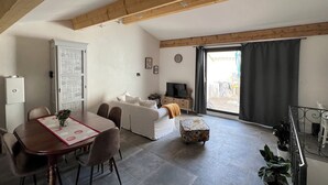 Un salon moderne comprenant un coin repas, un canapé, un téléviseur et un balcon avec vue.