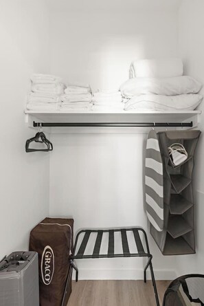 A neatly organized room with a bed, a small table, a storage unit, and a shelf. - Exquisite 1BR 30 min to FIFA (Bayonne)