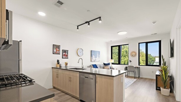 A modern kitchen with a central island, built-in dishwasher, and a dining area with a view. - Exquisite 1BR 30 min to FIFA (Bayonne)