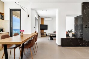 Un salon moderne comprenant un coin repas, un téléviseur à écran plat et une vue sur l’océan.