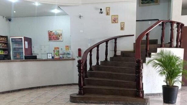 Un área de recepción con una escalera de madera, suelo de baldosas y mostrador de recepción.