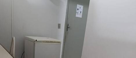 Una habitación pequeña con una cama individual, un escritorio y un refrigerador.