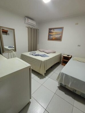 A dormitory room with two beds, a mirror, an air conditioner, and a painting on the wall. - HOTEL INTERNACIONAL (Cianorte)