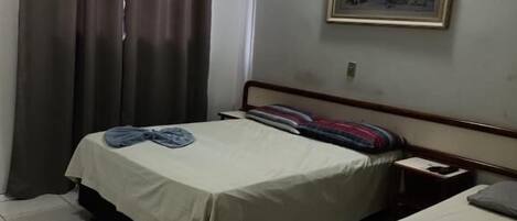 A room with two beds, a painting on the wall, and a curtain.