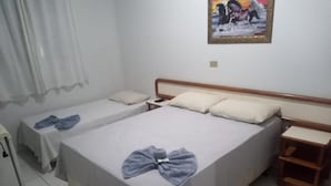 Un dormitorio con dos camas, una mesita de noche, una pequeña mesa, un cuadro en la pared y una cortina.