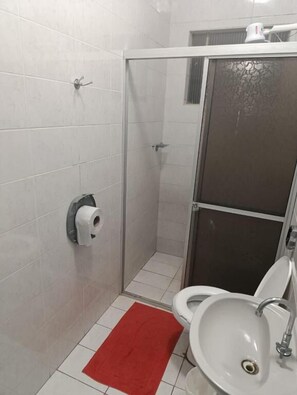 A small bathroom with a toilet, sink, and shower. - HOTEL INTERNACIONAL (Cianorte)