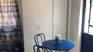 A room with a white wardrobe, a blue table with a vase, and a patterned curtain.