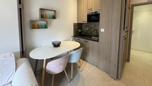 Una cocina moderna con armarios de madera, horno empotrado y una mesa de comedor blanca con dos sillas.