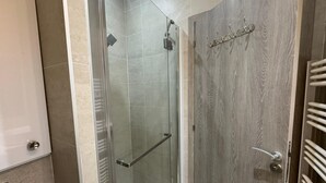 Un box de ducha con paredes de vidrio, puerta de madera y un perchero para toallas.
