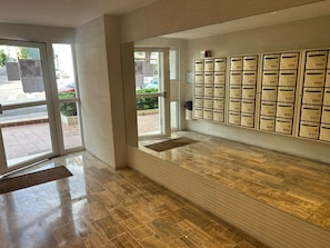 A lobby with a glass door entrance, a wall-mounted mail slot system, and a polished wooden floor. - Studio Cosy - Terrace & Air conditioning - 5m Festival & beach (Cannes)