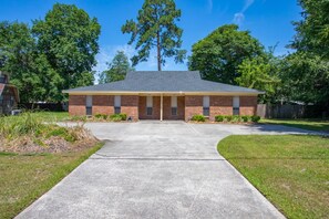 A two-story brick building with a flat roof, a covered front porch, and a concrete driveway leading to the entrance.
