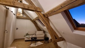 Une chambre de style « loft » avec un plafond en pente, une fenêtre intégrée, un canapé et une petite table.