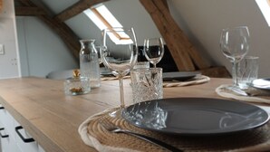 Une table à manger dressée avec des assiettes, des verres et un vase.