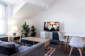 A modern living room with a TV, sofa, coffee table, and a small desk area. - Fairhaven View by Guestz (Lytham-St-Annes)