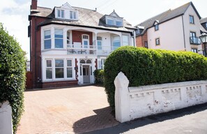 A two-story house with a white facade, a balcony, and a paved driveway. - Fairhaven View by Guestz (Lytham-St-Annes)