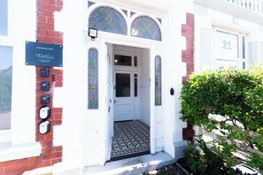 A building entrance with a white door, a signboard, and a number '21' on the wall. - Fairhaven View by Guestz (Lytham-St-Annes)