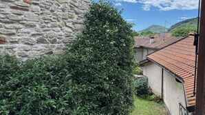 A stone wall, a bush, and a building with a tiled roof.