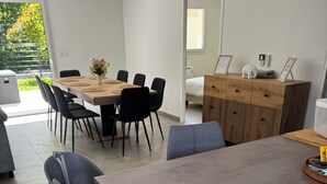 A modern dining area with a long table, chairs, and a wooden cabinet.