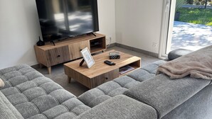 A modern living room with a large grey sectional sofa, a wooden coffee table, and a flat-screen TV on a wooden stand.