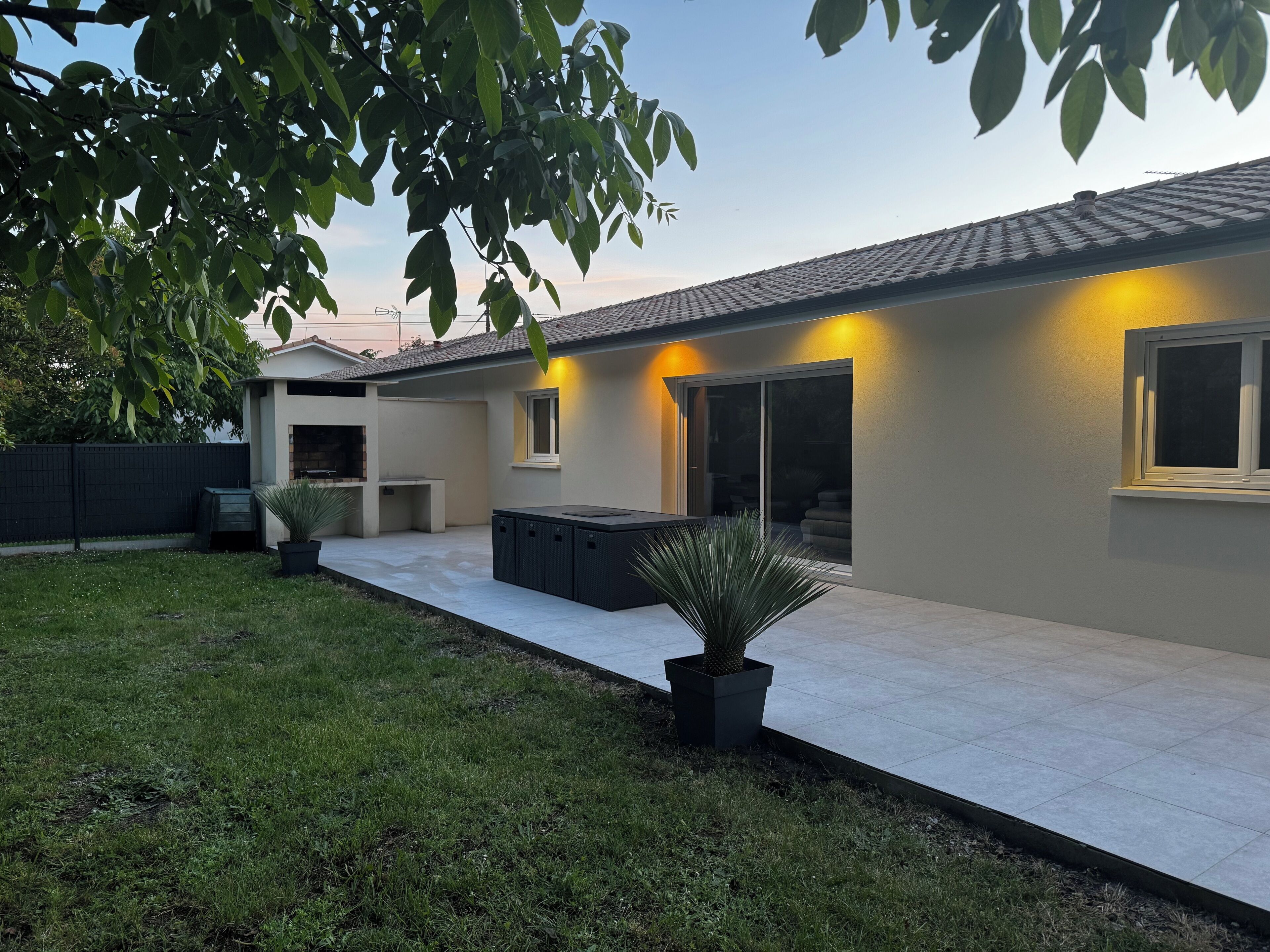 A modern house with a patio, a barbecue area, and a large window.