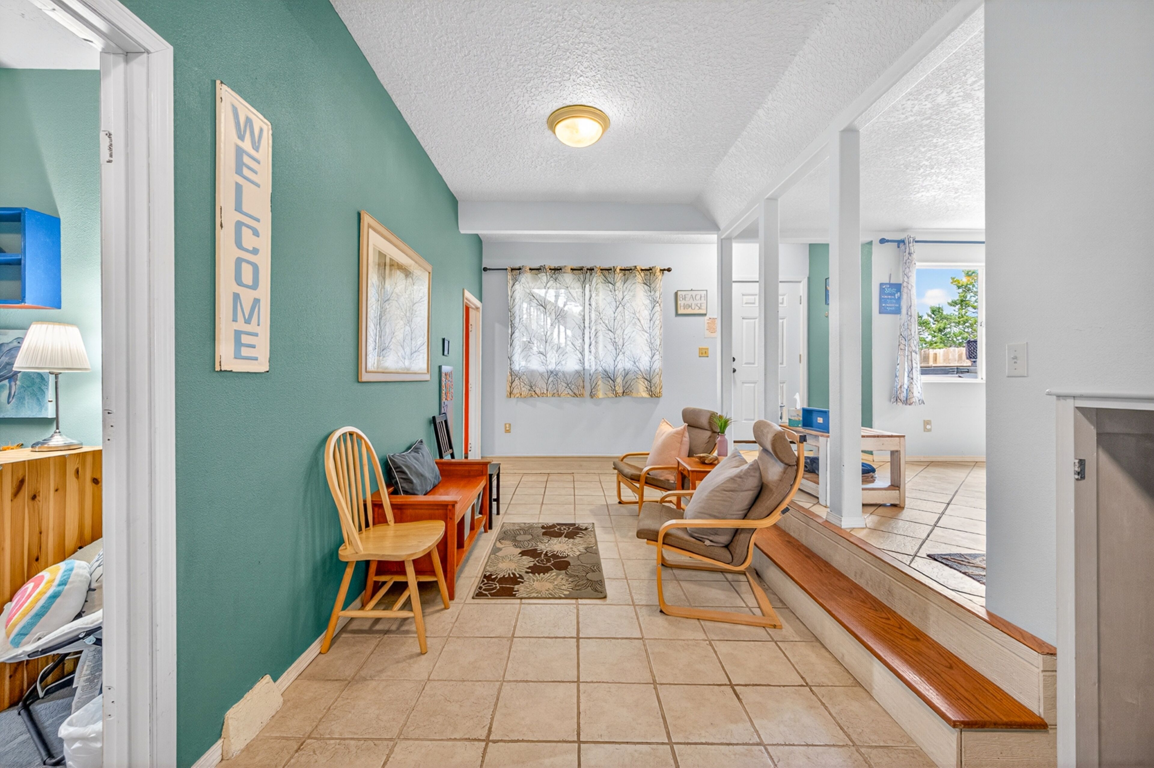 Una sala de estar con un cartel que dice 'WELCOME', muebles de madera, una alfombra y vistas al exterior.