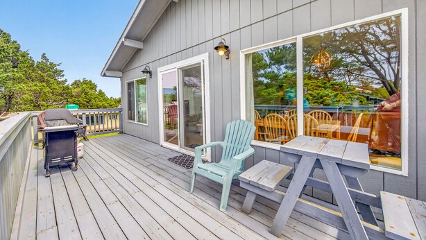 Une terrasse avec coin salon extérieur, un barbecue et une grande fenêtre donnant sur un jardin.
