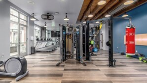 A gym with treadmills, weight machines, and a punching bag. - Landing Apartments Charlotte - NoDA (Charlotte)