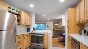 A modern kitchen with wooden cabinets, stainless steel appliances, and a built-in oven. - Central Gem ~ Backyard Oasis with Hot Tub and Firepit (Arvada)