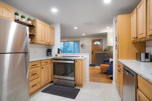 A modern kitchen with wooden cabinets, stainless steel appliances, and a built-in oven. - Central Gem ~ Backyard Oasis with Hot Tub and Firepit (Arvada)