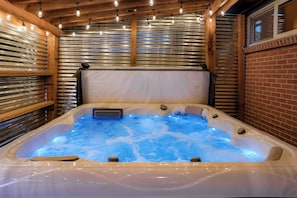 A hot tub with a wooden ceiling and metal walls, surrounded by string lights. - Central Gem ~ Backyard Oasis with Hot Tub and Firepit (Arvada)