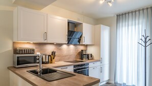 A modern kitchen with white cabinetry, a wooden countertop, and stainless steel appliances.