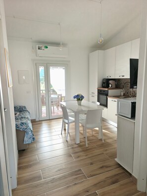 Eine moderne Küche mit weißen Schränken, einem Esstisch mit Stühlen, einer Mikrowelle und einer Kaffeemaschine.