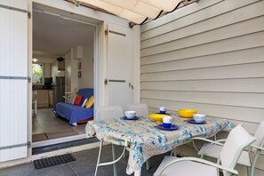 Eine offene Terrasse mit Esstisch, einer Couch und einer Küche im Hintergrund.
