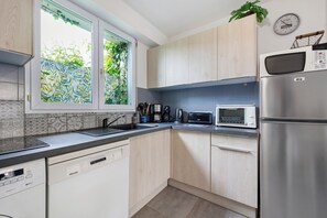 A modern kitchen with a dishwasher, microwave, and stainless steel refrigerator. - Holiday Home 'Gîte « le Bel Air »' with Private Terrace, Private Garden and Wi-Fi (Saint-Gilles-Croix-de-Vie)