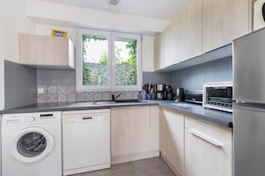 A modern kitchen with a washing machine, dishwasher, microwave, and coffee maker. - Holiday Home 'Gîte « le Bel Air »' with Private Terrace, Private Garden and Wi-Fi (Saint-Gilles-Croix-de-Vie)