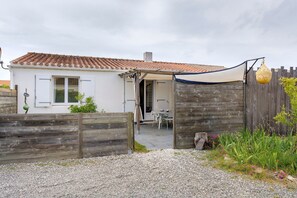Ein Haus mit einem Ziegeldach, Holzzaun und einem Schotterweg.