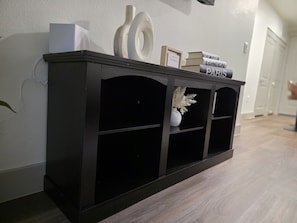A dark wooden console table with books and a small framed picture against a white wall. - Cozy 1-bedroom apartment in charming Addison (Addison)