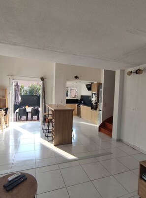A spacious living area with a kitchen, dining area, and a view of the outside. - Villa Torreilles Plage 4 People (Torreilles)