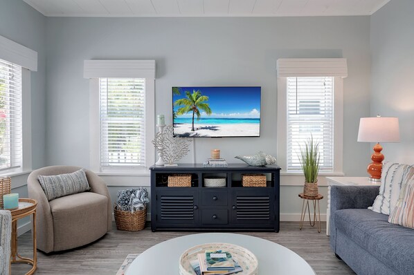 A living room with a beach-themed TV, a sofa, a coffee table, and a side table with a lamp.