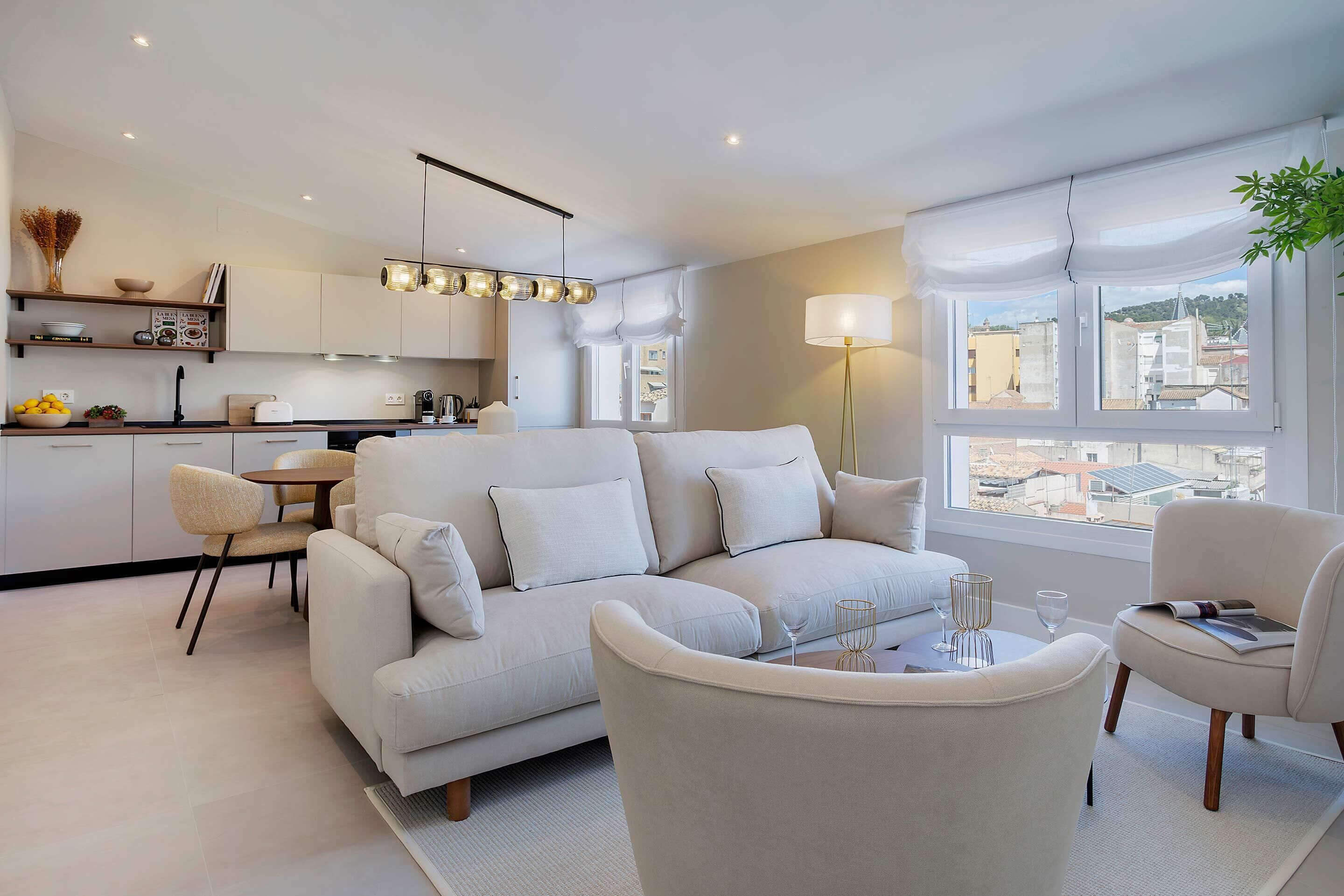 Una sala de estar moderna con un sofá, sillas, una mesa de comedor y una cocina al fondo.