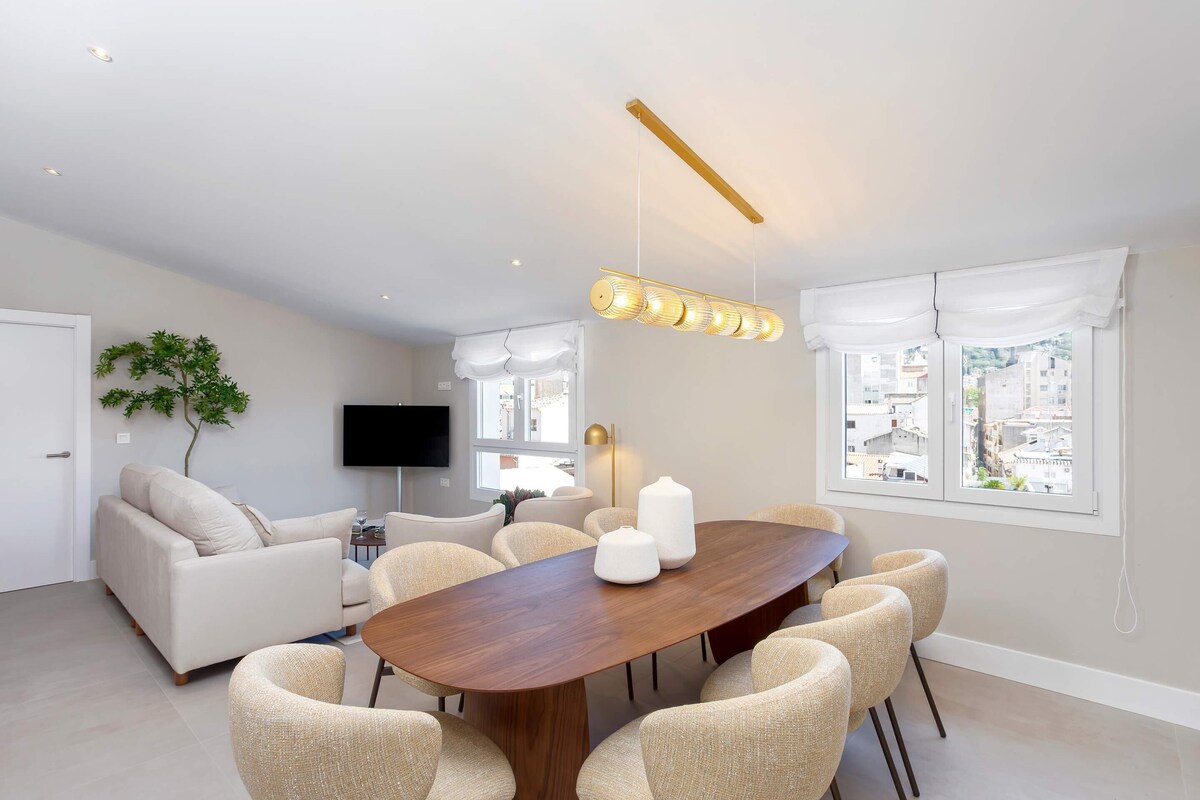 Una sala de estar moderna con una mesa de comedor de madera, sofás beige y un televisor de pantalla plana.