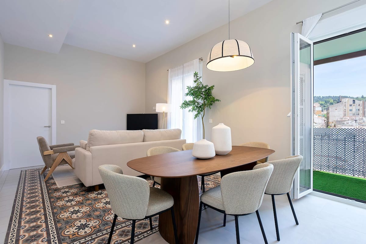Un salon moderne comprenant un coin repas, un canapé, un téléviseur et une grande fenêtre offrant une belle vue.